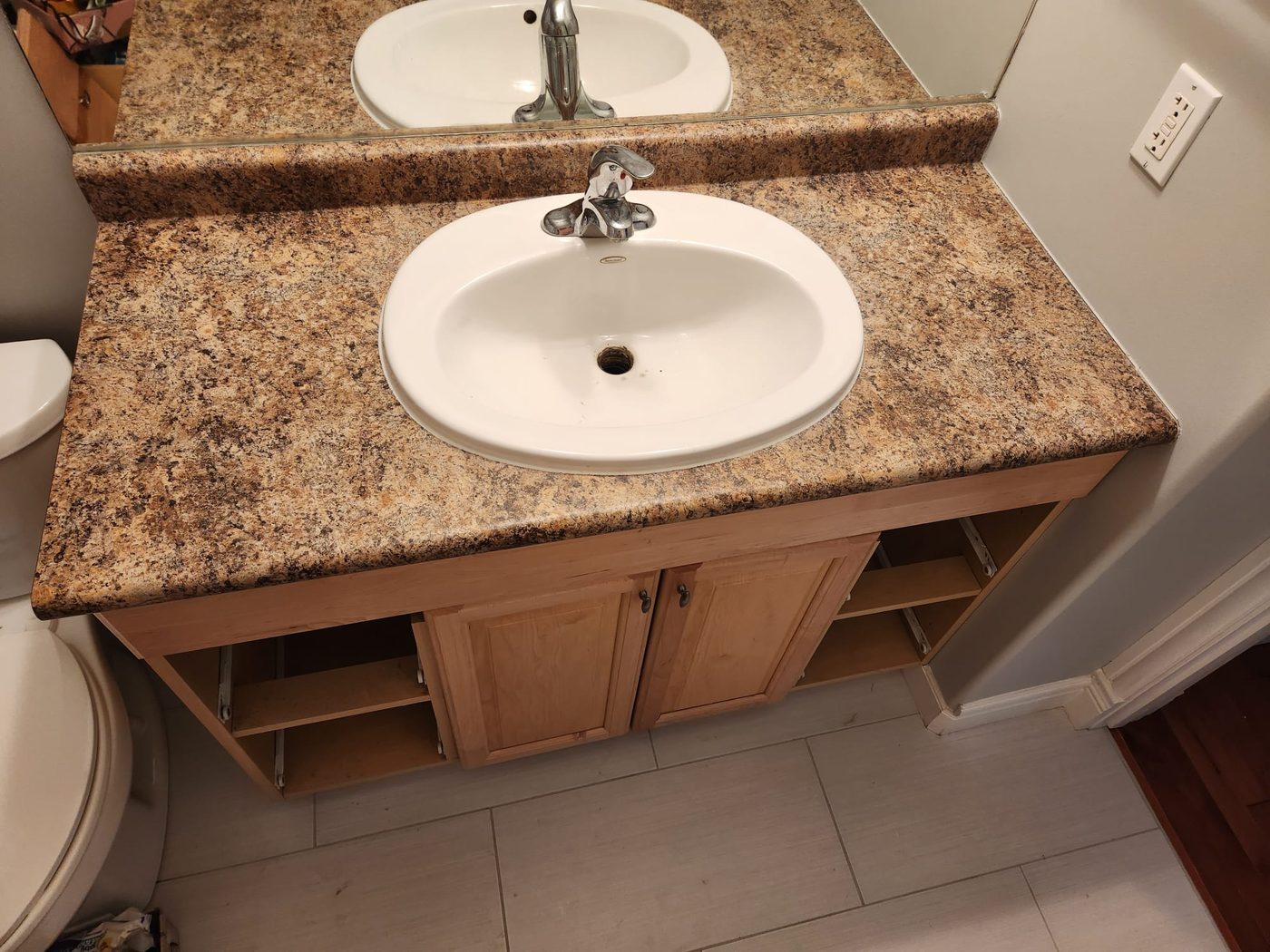 Bathroom vanity before: dated brown granite top with an old drop-in sink